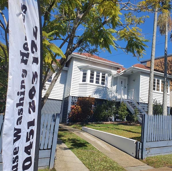 a big white house with house washing heroes banner outside