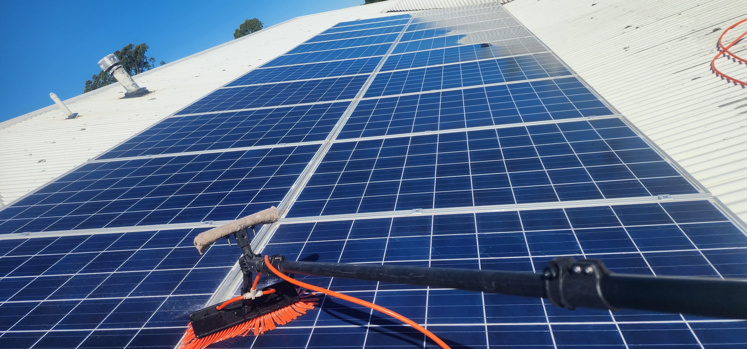 House Washing Heroes technician cleaning solar panels on a Brisbane home using a purified water system.